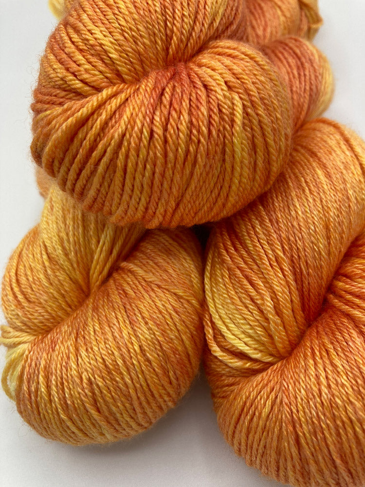 Stack of twisted hanks of Blazing Sun silk blend yarn by Red Door Fibers (yellow orange lighty variegated)