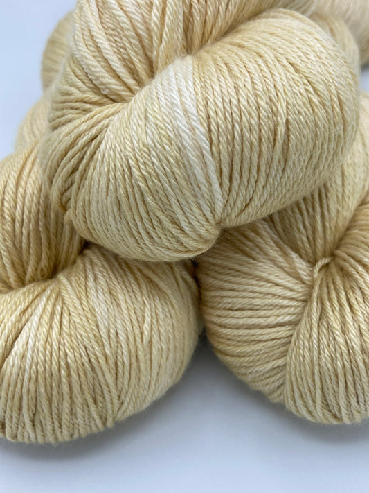 Three twisted hanks of Cornsilk silk blend yarn by Red Door Fibers