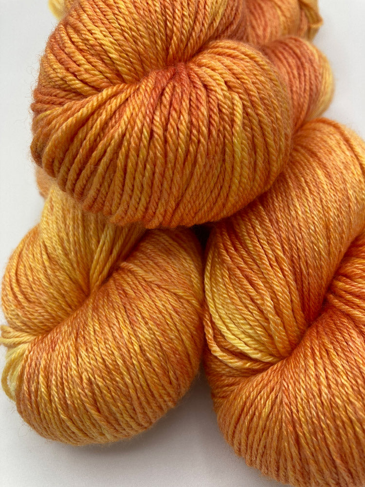 Stack of twisted hanks of Blazing Sun silk blend yarn by Red Door Fibers (yellow orange lighty variegated)
