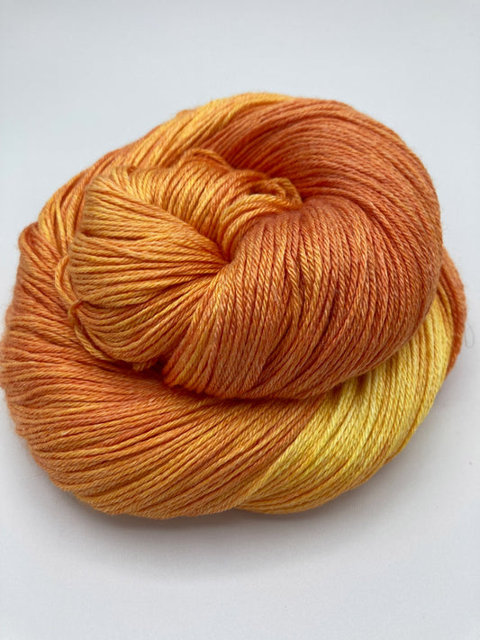 Rolled hank of Blazing Sun silk blend yarn by Red Door Fibers (yellow orange lighty variegated)