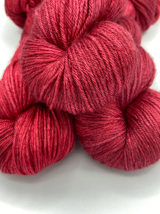 Three twisted hanks of Ruby Slippers silk blend yarn by Red Door Fibers (tonal)
